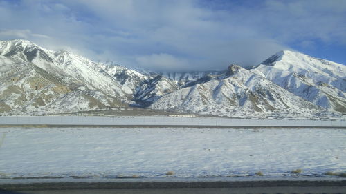 Scenic view of snow covered mountains against cloudy sky