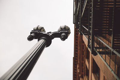 Low angle view of street light by building against clear sky