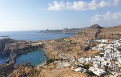 High angle view of townscape and natural harbour of lindos by sea against sky