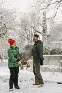 Man and woman carrying christmas tree at winter