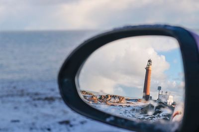 Close-up of side-view mirror with reflection