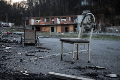 Empty chairs and table against abandoned building