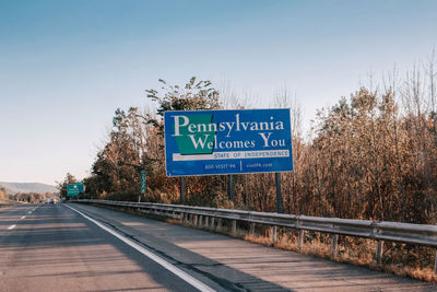 Information sign by road against clear blue sky