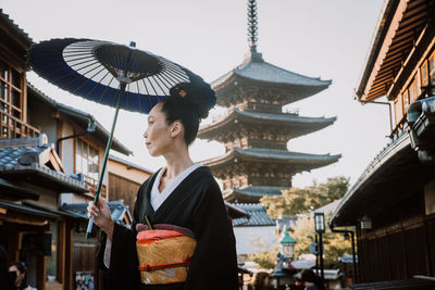 Woman standing by buildings in city