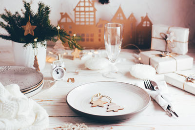  plate, cutlery, champagne glass and christmas decorations. tablescapes on white wooden table