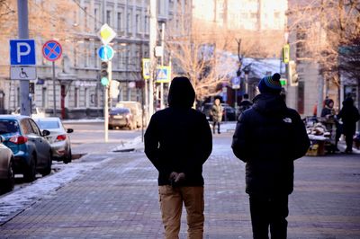 Rear view of people walking on city street