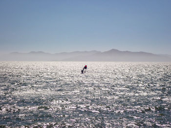 Man surfing in sea against clear sky