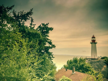 Lighthouse by sea against sky