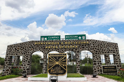 Information sign in front of building against cloudy sky