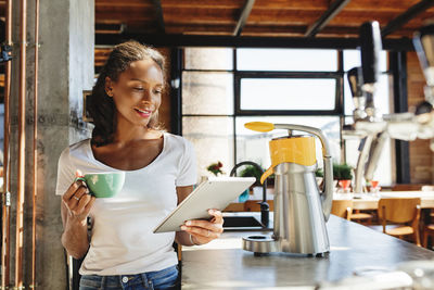 Woman holding coffee while standing at home