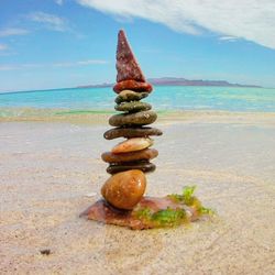 Close-up of stack on sand at beach against sky