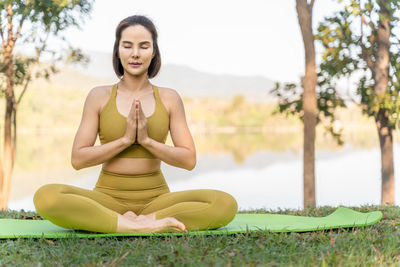 Young attractive woman closes her eyes while meditating during her morning yoga outdoor practice