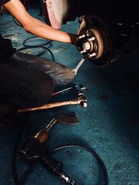 Midsection of male worker repairing car at workshop