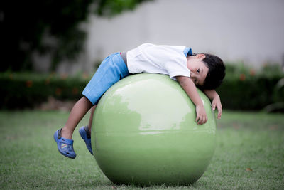 Cute boy lying on fitness ball at field