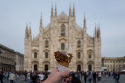 Close-up of hand holding ice cream with people in background