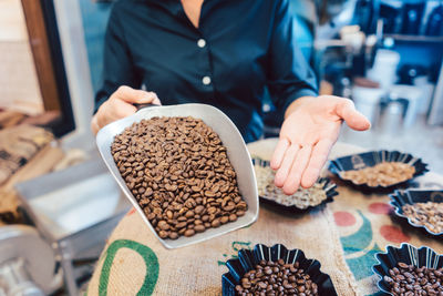Midsection of woman holding roasted coffee beans on table