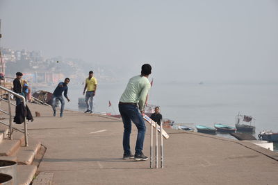 People standing on beach against clear sky