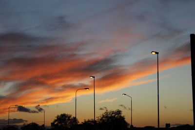 Low angle view of street lights against sky during sunset