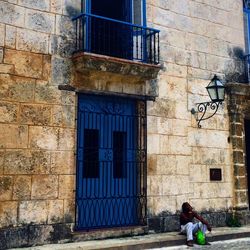 Man sitting on footpath against building