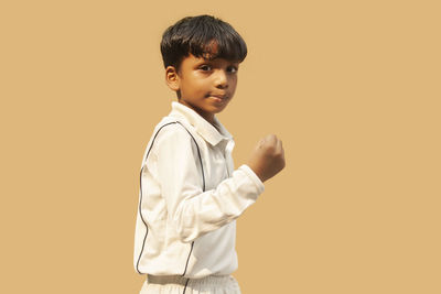 Portrait of boy standing against orange background