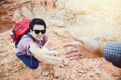 Cropped image of man giving hand to friend while climbing on mountain