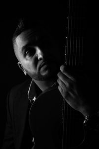 Man with guitar against black background