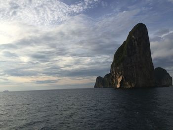 Rock formation in sea against sky during sunset