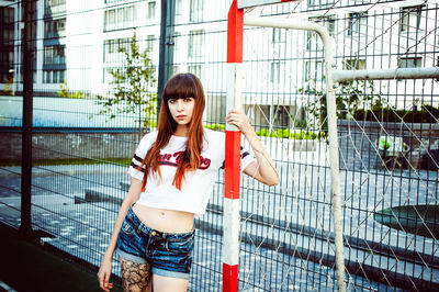 Portrait of young woman standing by soccer goal post