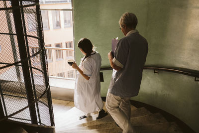 Female doctor and senior nurse moving down steps at medical clinic