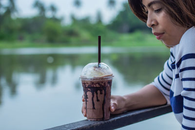 Woman having coffee against lake