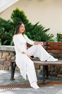 Portrait of young woman sitting on bench at park