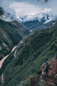 Male hiker standing on mountain against cloudy sky