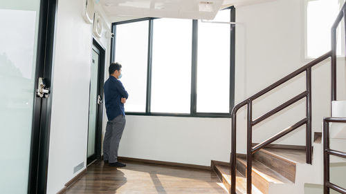 Full length portrait of man wearing mask looking through window