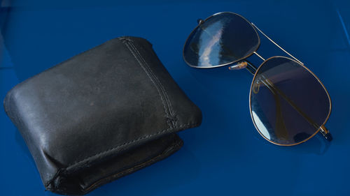 Low angle view of sunglasses on table against blue sky