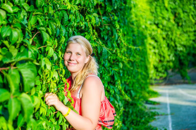 Portrait of young woman standing amidst plants