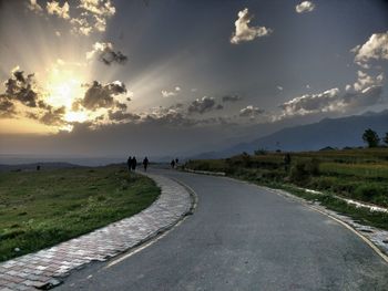 People on road against sky during sunset