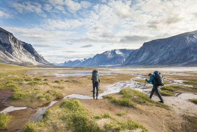 Backpackers hiking through akshayak pass, baffin island, canada.