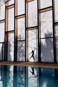 Woman in swimming pool against sky seen through window