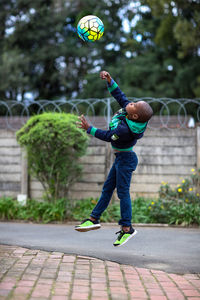 Full length of boy throwing ball on street