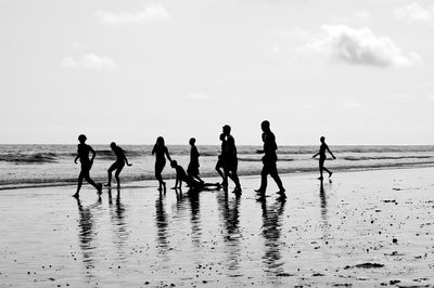 Silhouette people on beach against sky
