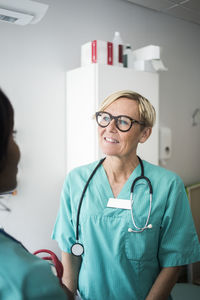 Smiling mature pediatrician talking to female healthcare worker in clinic