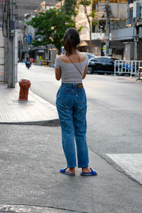 Rear view of woman standing on footpath in city