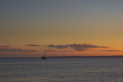 Silhouette sailboat in sea against sky during sunset