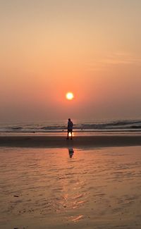 Silhouette man standing on beach against sky during sunset