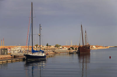 Sailboats moored at harbor