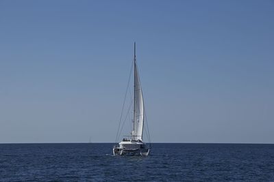 Sailboat sailing on sea against clear sky