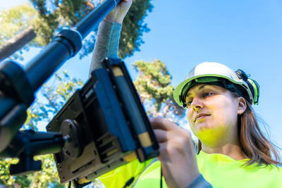Low angle view of woman using global positioning system equipment against clear sky