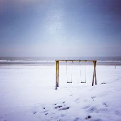 Wooden posts on beach against sky during winter