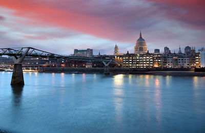 Illuminated city buildings against sky at dusk