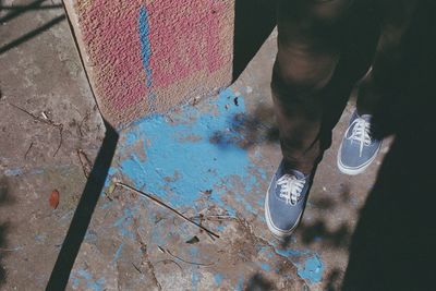 Low section of man walking by blue paint on footpath